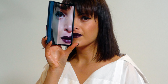 A model holds a Samsung Galaxy Fold smartphone to her face, during a media preview event in London. (AP Photo/Kelvin Chan)