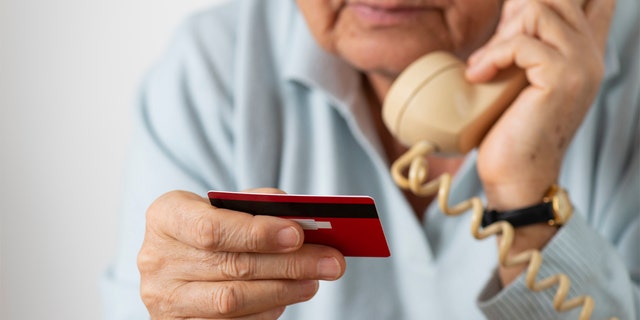 Woman using phone while holding credit card.