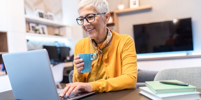 Senior woman working at home using laptop computer in the living room