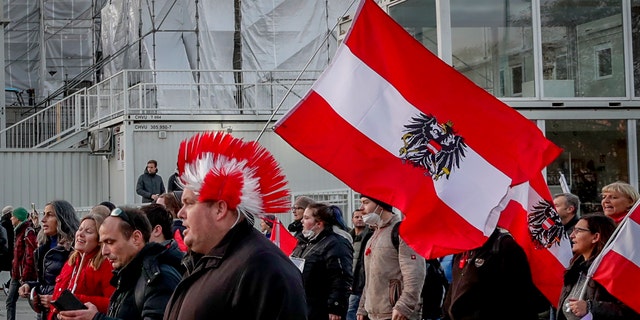 People walk past the parliament as they take part in a demonstration against the country's coronavirus restrictions in Vienna, Austria, Saturday, Nov. 20, 2021. (AP Photo/Lisa Leutner)