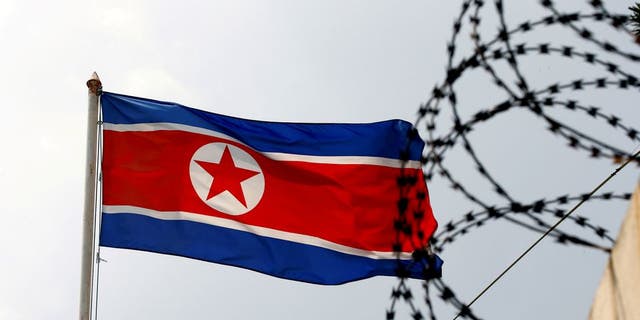 FILE- A North Korea flag flutters next to concertina wire.