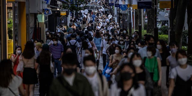 People walk along a crowded shopping street on July 24, 2021, in Tokyo.